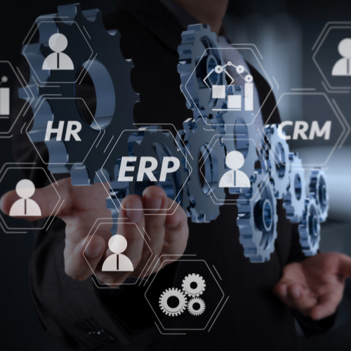 Business professional holding gears representing CRM and ERP systems, emphasizing automation and integration for smarter decision-making in operations.