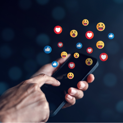Hand interacting with smartphone displaying social media reactions and emojis, illustrating engagement and brand visibility in digital marketing strategies.
